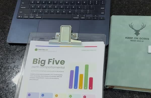 Foto real: teste Big Five impresso na prancheta ao lado do notebook